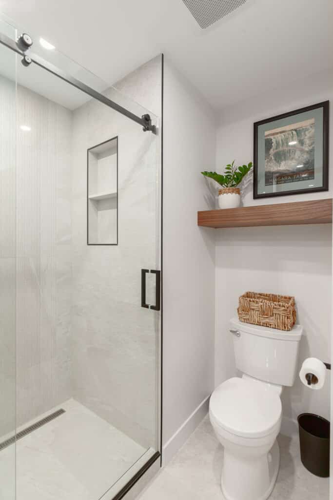 A white bathroom with a glass shower door featured in the Bathroom Gallery.