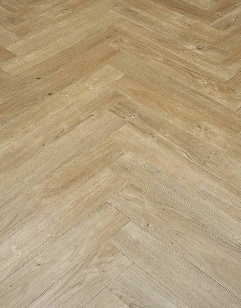 A close up of a wooden floor with a herringbone pattern.