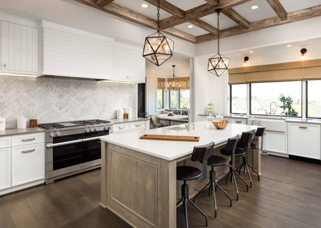 A white kitchen with wood beams and a center island, elegantly transforming the space.