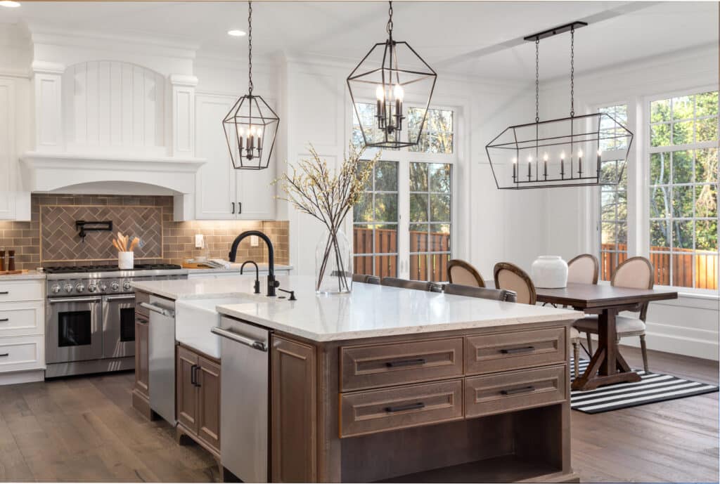 A kitchen with white cabinets, wooden flooring, and a counter height.