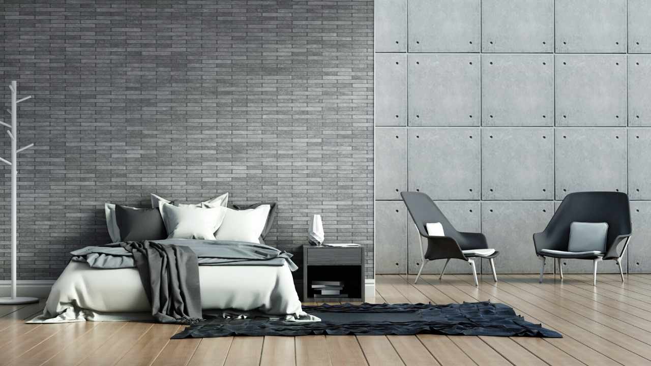 A bedroom with a grey brick wall and a white bed.