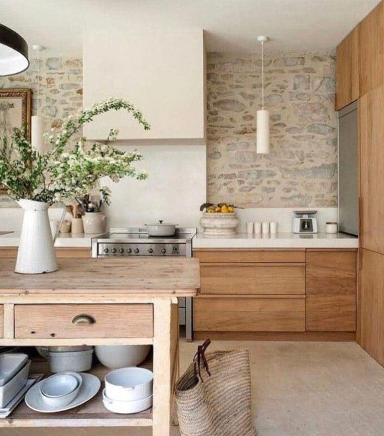 A kitchen with wooden cabinets and stone walls featuring cabinet hardware.