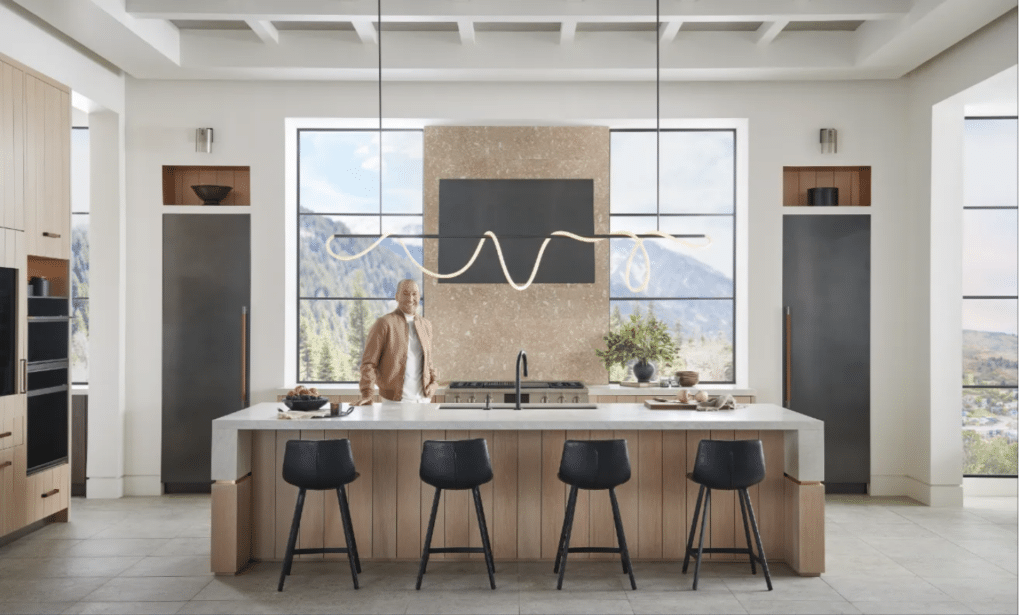 A modern kitchen with a large island and black stools.