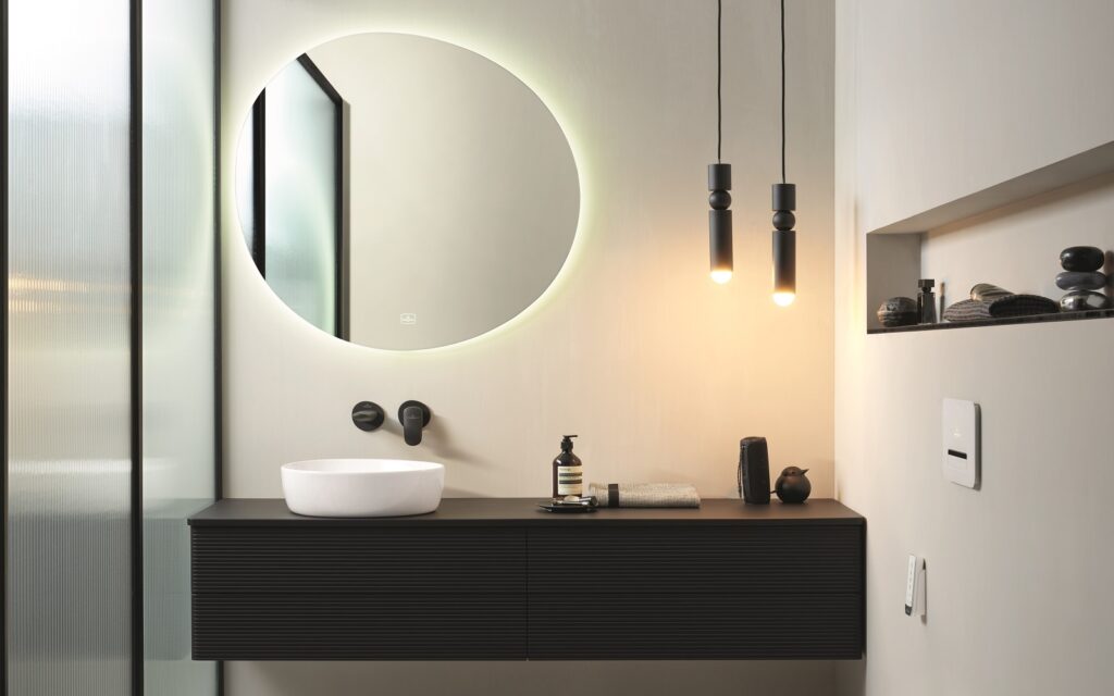 A black and white bathroom with a round mirror.