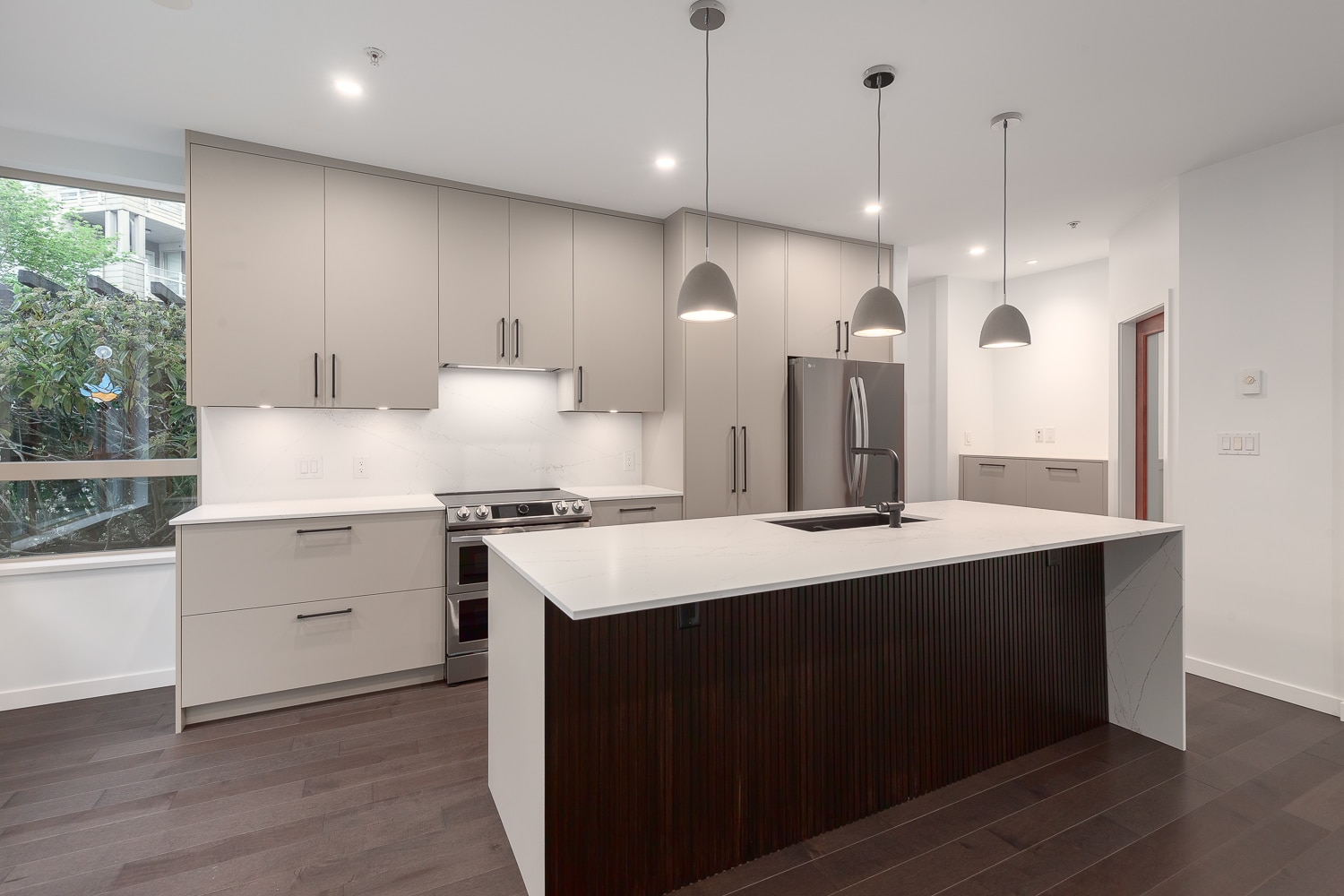 A kitchen with a white cabinet layout and wood floors.