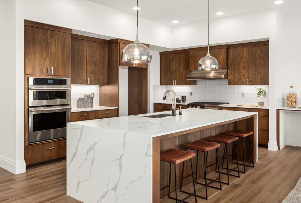 A kitchen with elegant marble counter tops and lustrous wooden cabinets.