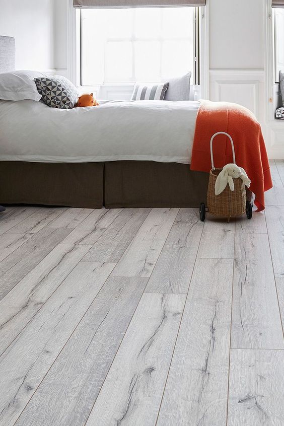 A North Vancouver bedroom with white laminate flooring and a bed.