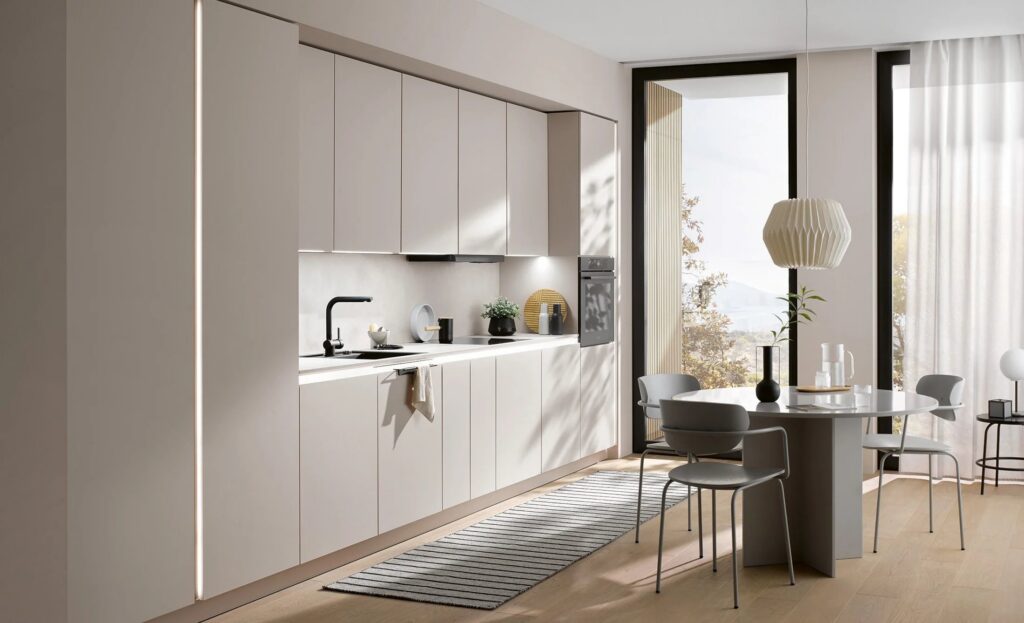 Modern kitchen with neutral cabinetry, built-in appliances, a dining table with four chairs, a pendant light, and a large window letting in natural light.