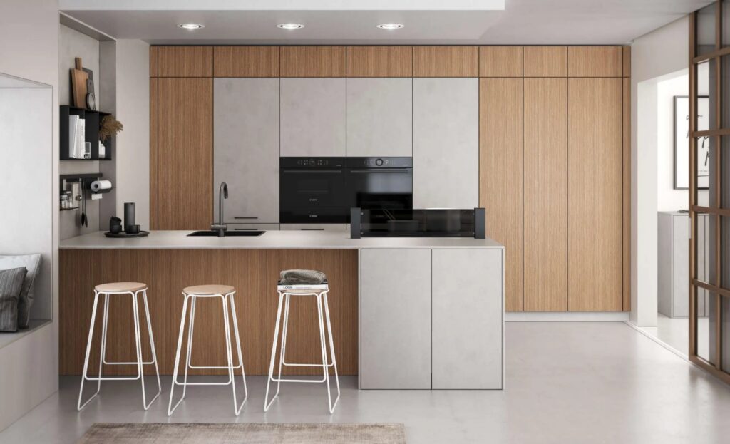 Modern kitchen with wood and white cabinets, built-in oven, black appliances, island with two towels, and three white bar stools.