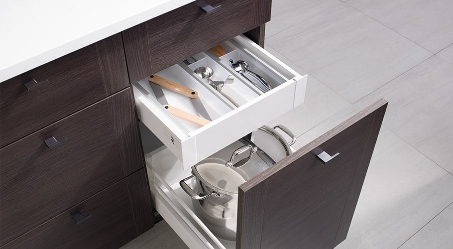 A white kitchen cabinet with a drawer full of utensils.