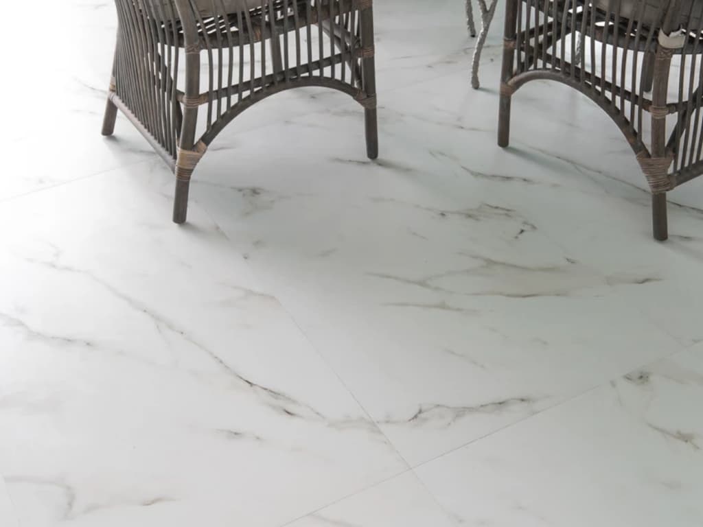 A white marble floor enhances the elegance of a space, paired with complementing wicker chairs for a refined touch.