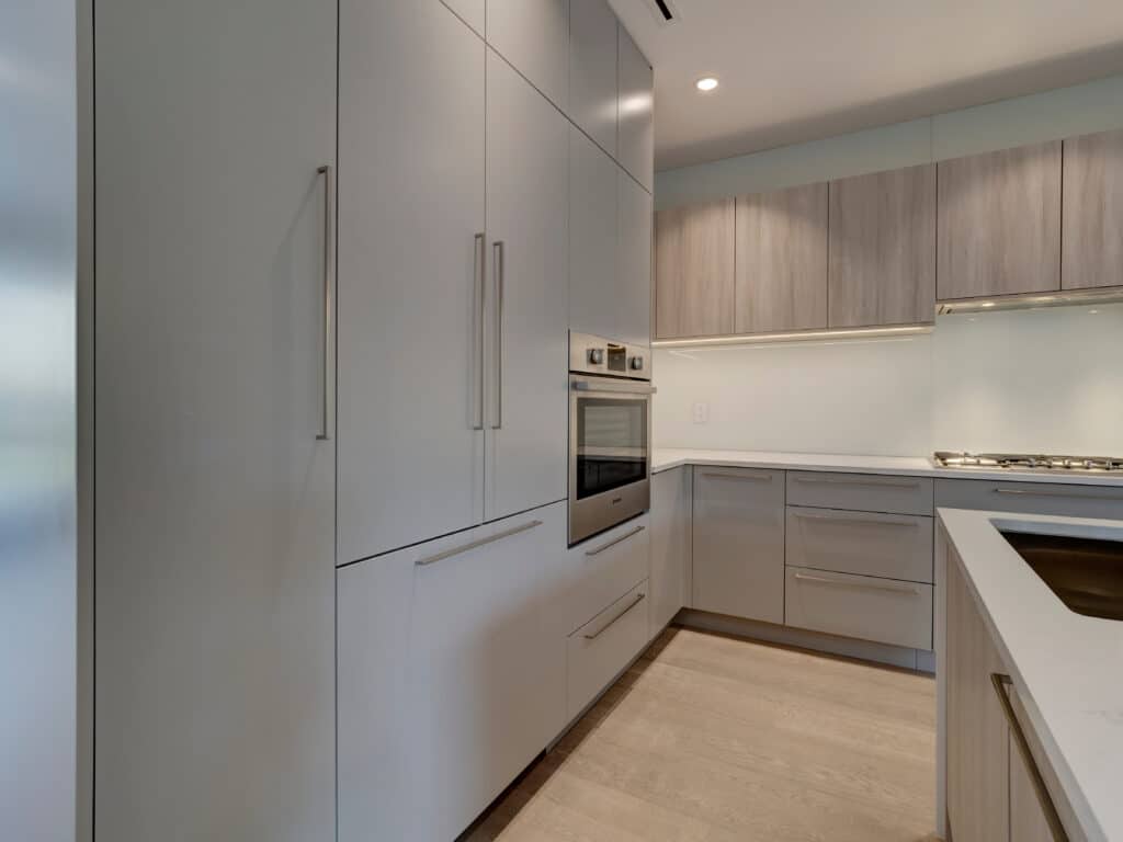 A modern kitchen with white cabinets and stainless steel appliances in Vancouver Renovation Photos