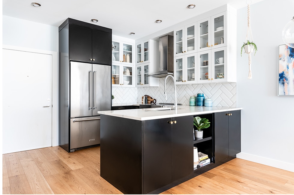A modern black and white kitchen with wooden floors in a condo setting.