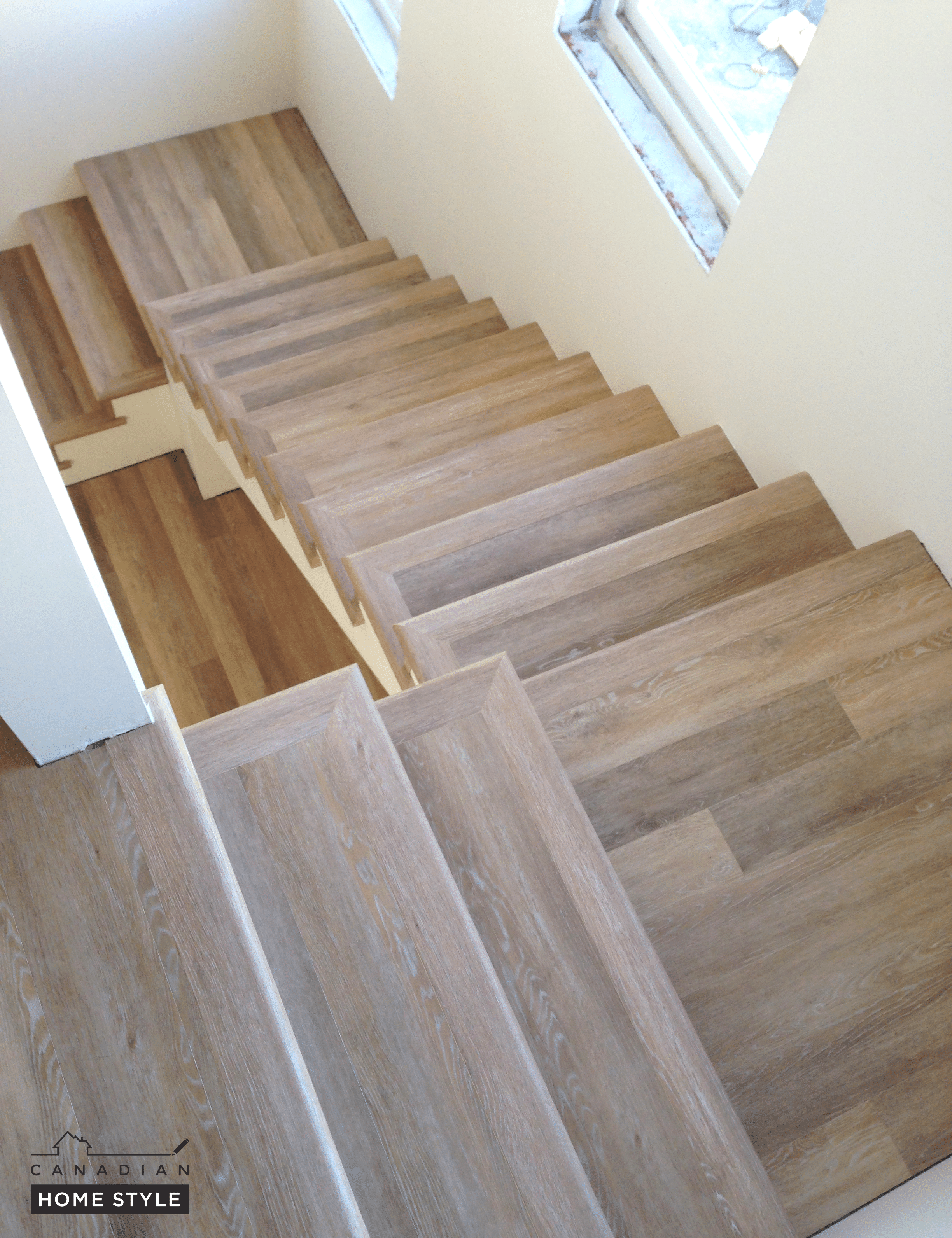 A stairway with wood flooring and a vinyl window.