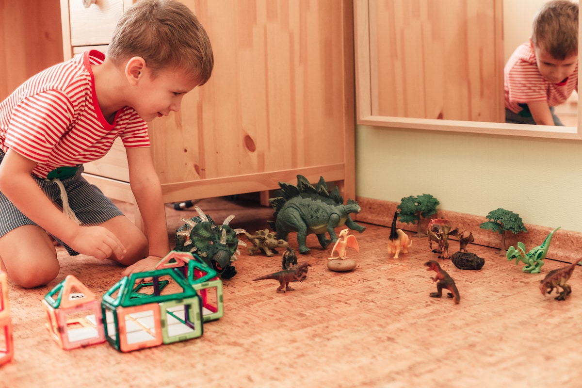 A young boy playing with toy dinosaurs on the Vancouver cork flooring.