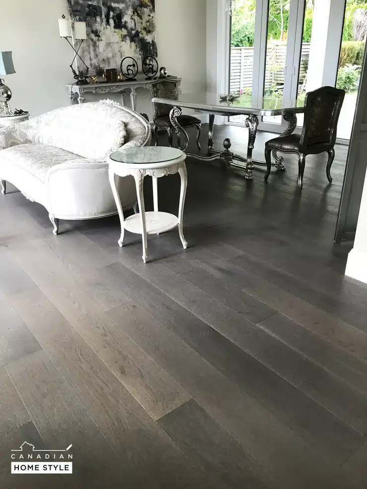 A living room with various types of flooring, including grey hardwood floors.