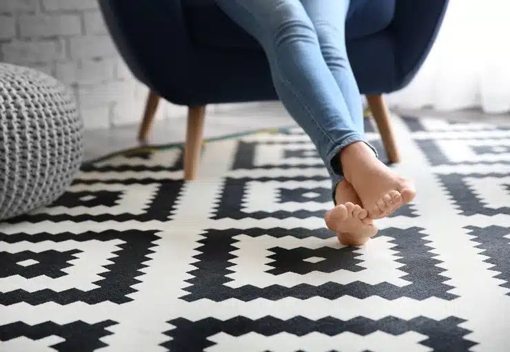 A woman's feet on a black and white rug enhanced with a healthier choice carpet underlay.