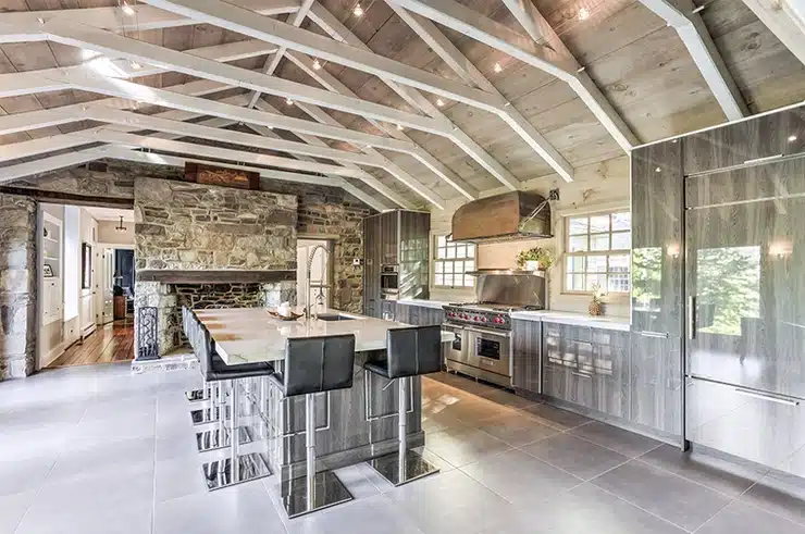 A large kitchen with a stone counter top and stainless steel appliances is enhanced by the elegant craftsmanship of Cabico Elmwood cabinets from Cabinet of Canada.