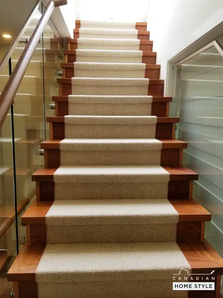 A staircase with beige wool carpet and glass railings in Vancouver.