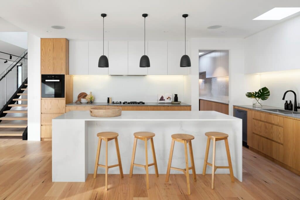 A low maintenance modern kitchen with wooden floors and stools.