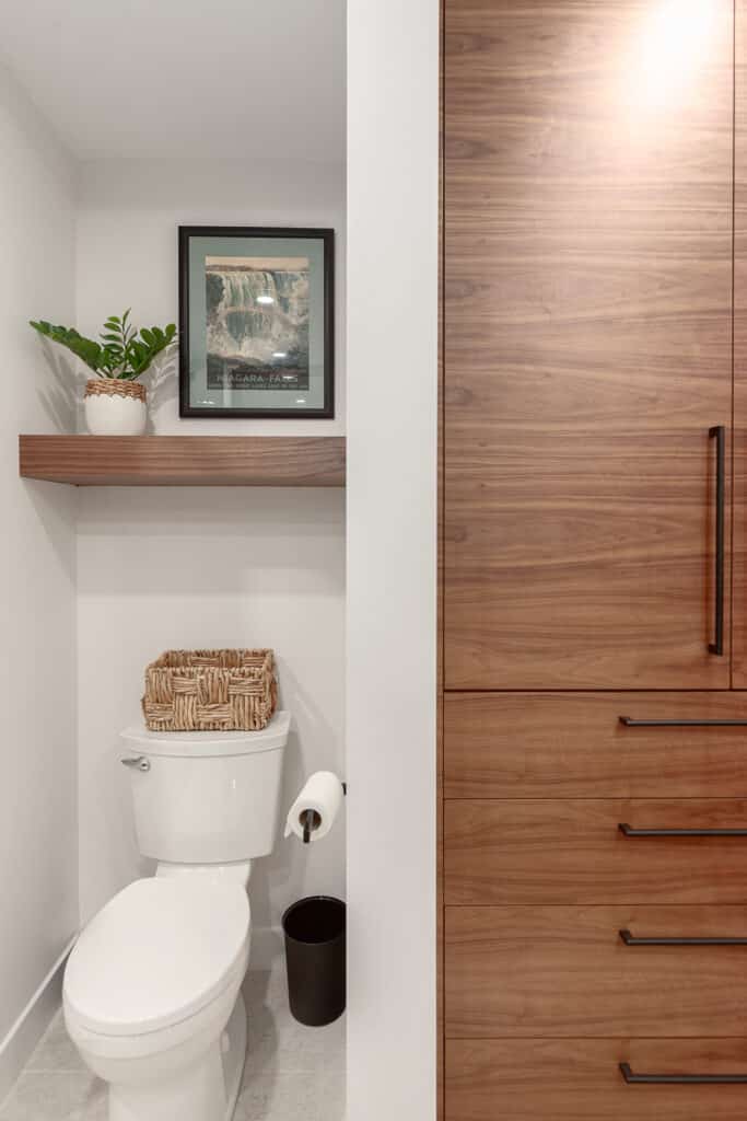 A bathroom with a wood cabinet and a toilet designed with elements of kitchen and bath design.