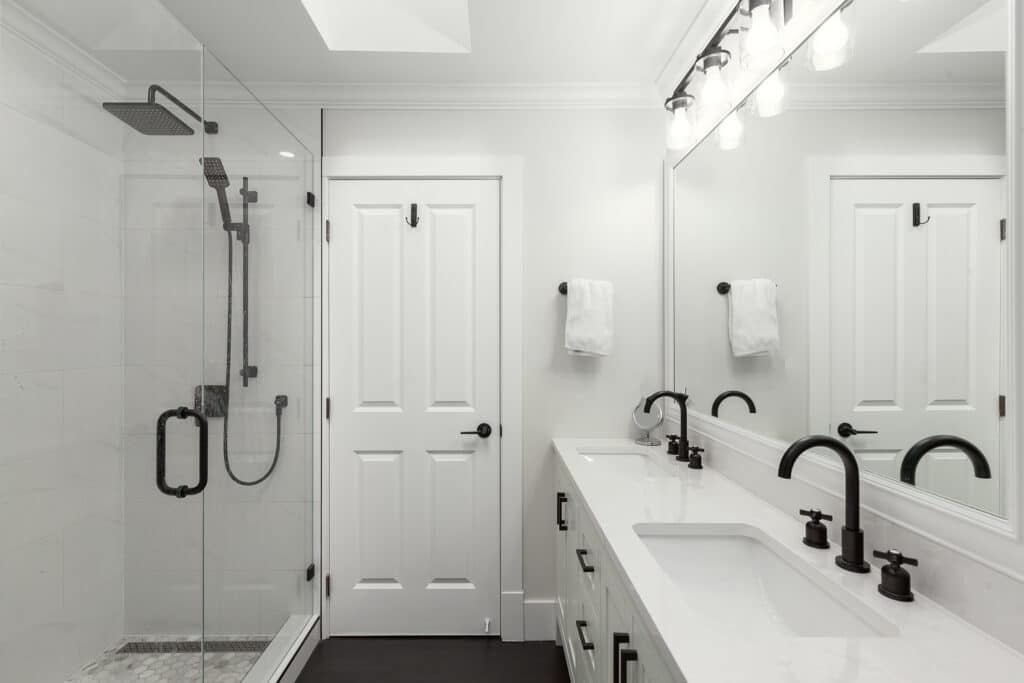 A white and black bathroom with a walk in shower in a Bathroom Gallery.