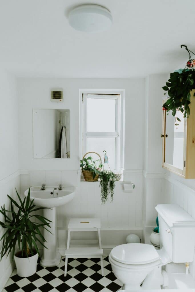 A bathroom with a black and white checkered floor undergoing repairs for a leaking ceiling.