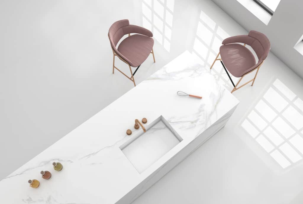 An aerial view of a white kitchen with pink chairs showcasing beautifully maintained marble countertops.