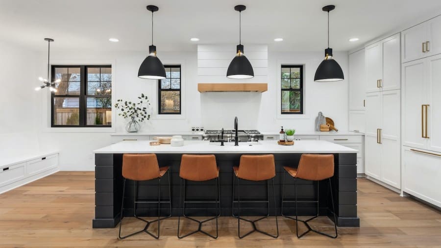 An open concept kitchen with black and white cabinets and stools.