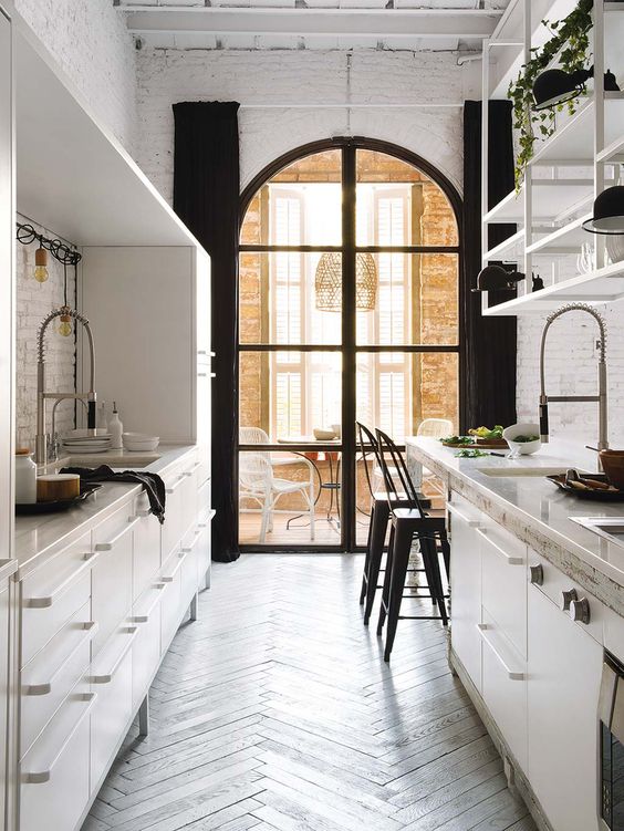 Ideal Kitchen Design: A white kitchen with wooden floors and an arched window stands as a perfect example of a thoughtfully curated space.