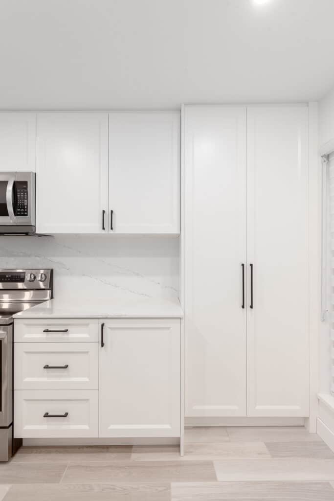 The kitchen in Vancouver features white cabinets and stainless steel appliances, delivering a modern and elegant look.