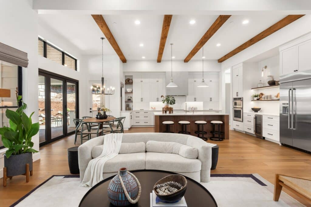 An open concept kitchen and living room with wooden beams.
