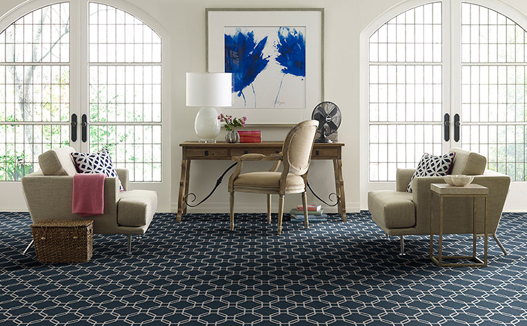 A living room with a blue rug and chairs enjoys the benefits of carpet flooring.