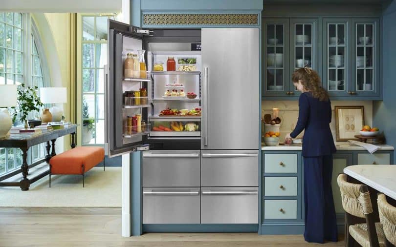 A woman opening the door of a refrigerator.
