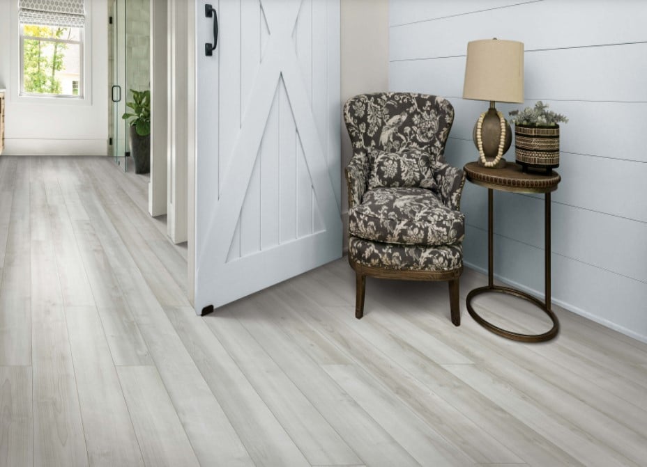 A hallway with luxurious Karastan wood floors and a comfortable chair.