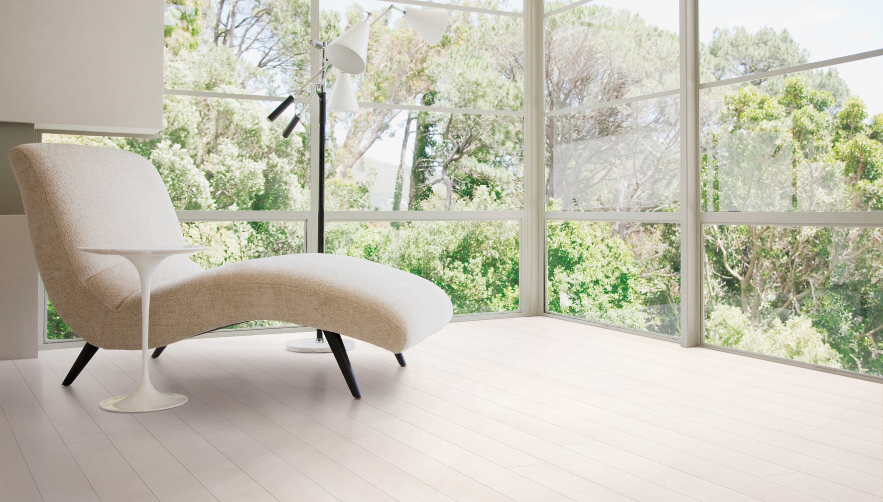 A white chair in front of a window in a room with hardwood flooring.